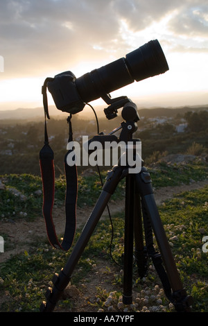 Dramatic late evening silhouette of camera with telephoto lens on tripod Stock Photo