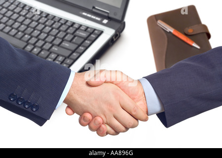 Business handshake with a laptop and a notepad in the background Stock Photo