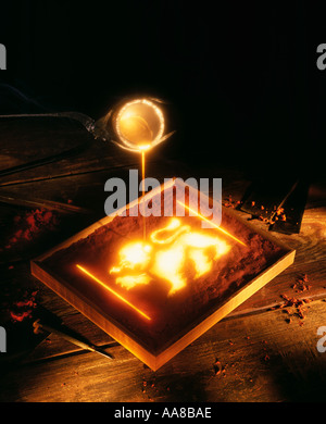MOLTEN GOLD POURING FROM CRUCIBLE TO FORM CASTING IN SHAPE OF A LION Stock Photo