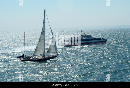 Red Funnel Jet Ferry Passing Yacht in Southampton Water on The Solent Hampshire England United Kingdom UK Stock Photo