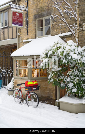 Delivering the post during winter snow in the Cotswold village of Bourton on the Water Gloucestershire UK Stock Photo