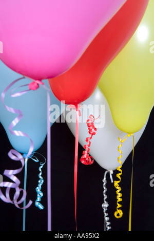 Multi-coloured balloons and curled ribbons against black background, close-up Stock Photo