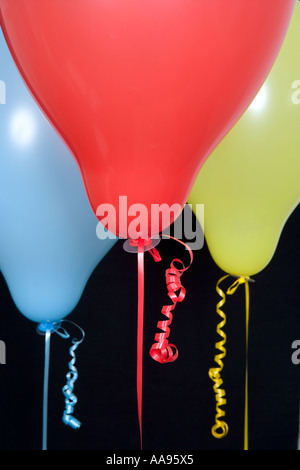 Multi-coloured balloons and curled ribbons against black background, close-up Stock Photo