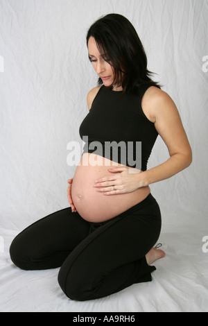 Pregnant Woman Kneeling Wearing a Black Vest and Trousers