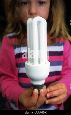 Young girl holding a long-life light bulb in her home, Suffolk, UK. Stock Photo