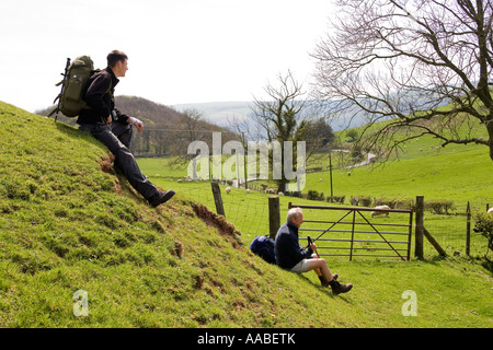 UK Wales Clwyd Eglwyseg Offas Dyke Path grandfather and grandson young and mature walkers resting in lush green landscape Stock Photo