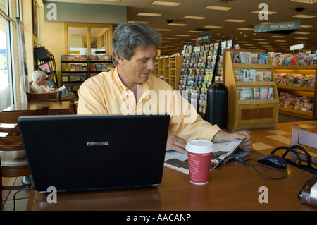 Middle-aged man using a laptop computer in a book store Stock Photo