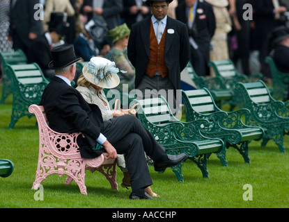 Elegant couple sitting on a pink bench in the royal enclosure at Royal Ascot Stock Photo