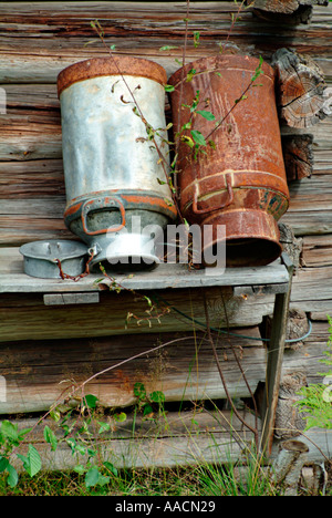two old rusted milk churns at wall of blockhouse Stock Photo