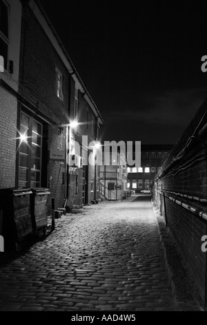 Dark and dangerous looking alley at night leading to industrial plant ...