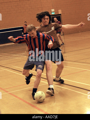 Sixth form college students play football in gym Stock Photo