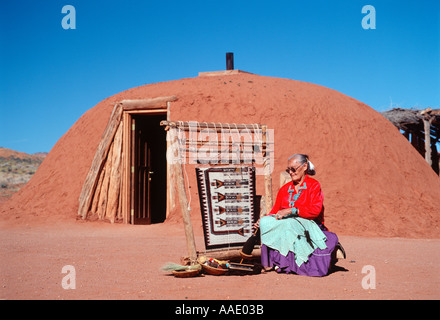 An elderly Native American woman weaves a traditional Navajo rug outside her hogan in northern Arizona Stock Photo