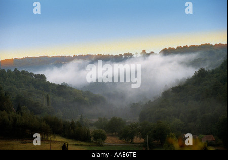 Early Morning Mist hangs in a valley in the Dordogne region of France Stock Photo