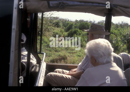 Elderly tourists watching a lioness from the window of an open sided LANDROVER Masai Mara Kenya Stock Photo