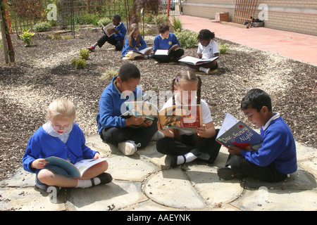 Primary school children in playground reading books Stock Photo