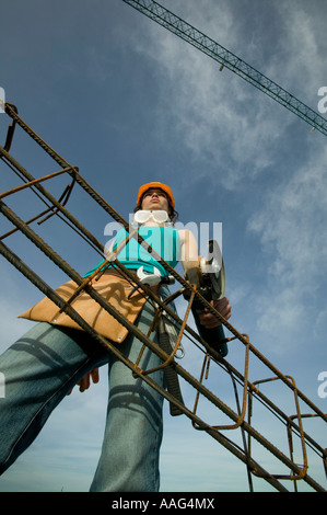 Female construction worker holding angle grinder with steel reinforcing Stock Photo