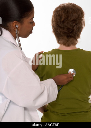 African American doctor using stethoscope to examine Caucasian female patient during routine check-up in the USA. Stock Photo