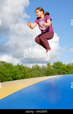 a young girl jumping on a big rubber trampoline Stock Photo