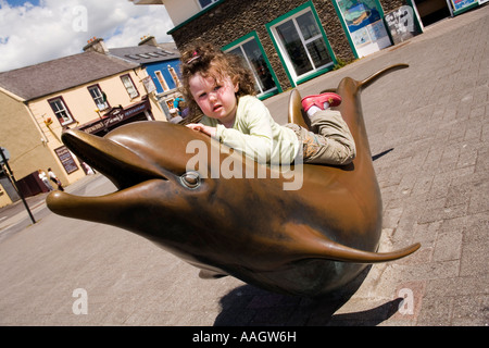 Ireland Kerry Dingle seafront girl riding bronze sculpture of Fungie the Dingle dolphin Stock Photo