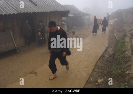 Northwest Vietnam Sapa Ethnic minorities man walking on adirtrack by a house in wet and foggy weather Stock Photo