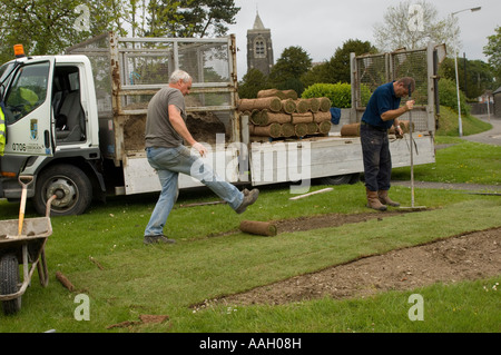 Two local authority direct labour employees laying new turf   on lawn Lampeter Ceredigion Wales Stock Photo