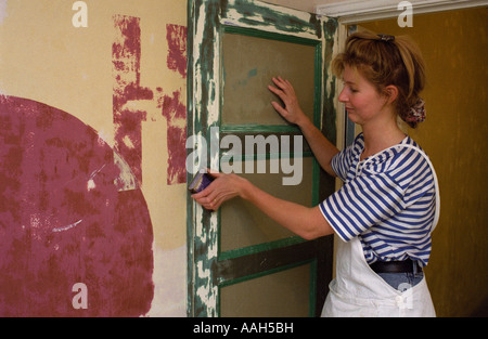 female trainee apprentice painter and decorator preparing a door ready for painting Stock Photo