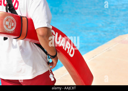 Life guard walking along a pool in a water park with a life saving buoy conceptual Stock Photo