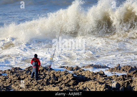 Man fishing on the North Devon coast at Westward Ho! in stormy seas. Stock Photo