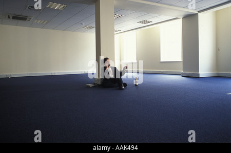 Young businessman in empty office space celebrating with Champagne Stock Photo