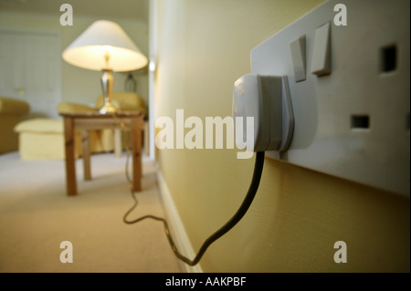 A table lamp plugged into a wall socket in the UK Stock Photo