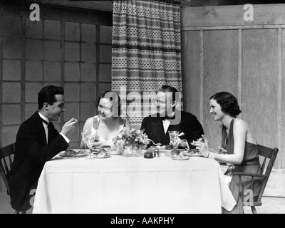 1930s TWO COUPLES MEN WOMEN FORMAL ATTIRE EATING DINNER Stock Photo