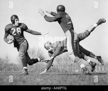 1940s THREE MEN PLAYING FOOTBALL LEATHER HELMETS ONE BLOCKING TACKLER WHO IS TRYING TO CATCH BALL CARRIER Stock Photo