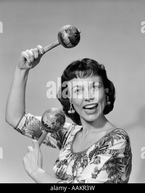 1950s WOMAN PORTRAIT PLAYING MARACAS LOOKING AT CAMERA Stock Photo