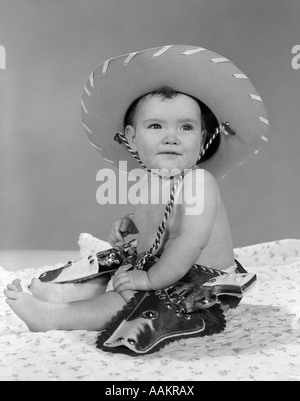1960s BABY GIRL WEARING COWBOY HAT TOY HOLSTER AND GUNS INDOOR