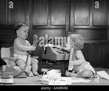 1960s 2 BABIES IN DIAPERS ONE ON CHAIR WITH TELEPHONE OTHER ON FLOOR WITH ADDING MACHINE PENCIL BEHIND EAR Stock Photo