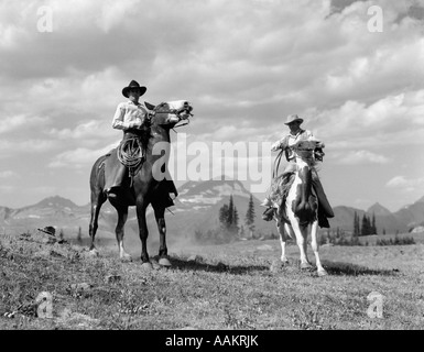 1930s PAIR OF COWBOYS ON HORSEBACK AT GLACIER FIFTY-MILE CAMP Stock Photo