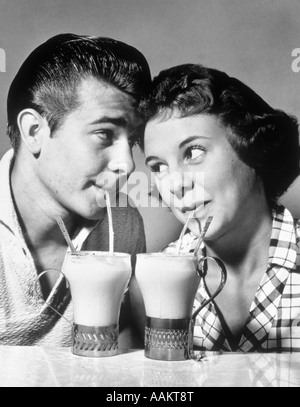 1940s 1950s ROMANTIC TEENAGE COUPLE BOY AND GIRL HEAD TO HEAD DRINKING ICE CREAM SODAS Stock Photo