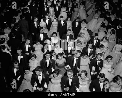 1950s GRAND MARCH AT HIGH SCHOOL PROM TEEN COUPLES WEARING FORMAL DRESS Stock Photo