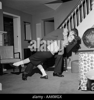 1960s TEENAGE COUPLE BOY & GIRL DANCING IN HOME LIVING ROOM DOING A BACKWARD DIP DANCE STEP Stock Photo