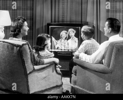 1950s FAMILY SITTING IN EASY CHAIRS WATCHING TELEVISION Stock Photo