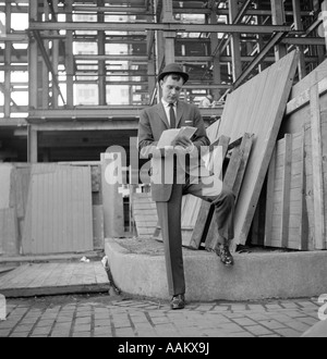 1960s MAN BUSINESS SUIT AT CONSTRUCTION SITE MAKING NOTES Stock Photo