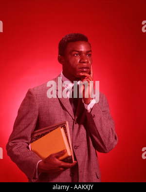 1960s AFRICAN AMERICAN MALE STUDENT CARRYING BOOKS Stock Photo