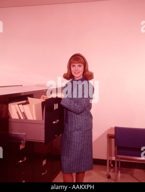 1960s SMILING WOMAN FILE CABINET LOOKING AT CAMERA Stock Photo