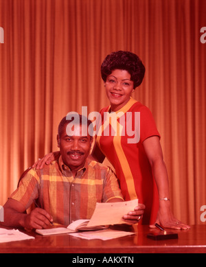 1960s 1970s AFRICAN AMERICAN COUPLE WORKING ON FAMILY FINANCES LOOKING AT CAMERA Stock Photo
