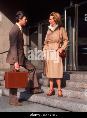 1960s BUSINESS MAN & WOMAN TALKING ON FRONT STEPS OFFICE Stock Photo