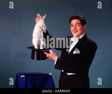 1960s 1970s MAN MAGICIAN TUXEDO PULLING RABBIT OUT OF TOP HAT MAGIC ILLUSION SLEIGHT OF HAND TRICK Stock Photo