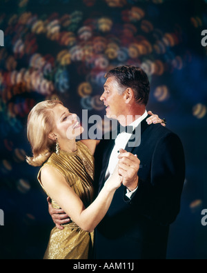 1960s COUPLE IN FORMAL CLOTHES DANCING MULTIPLE LIGHT BACKGROUND CELEBRATION ANNIVERSARY MAN WOMAN Stock Photo