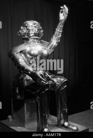 1930s ROBOT MAN MANUFACTURED FROM METAL SITTING HOLDING A GUN IN ITS HAND FUTURISTIC Stock Photo