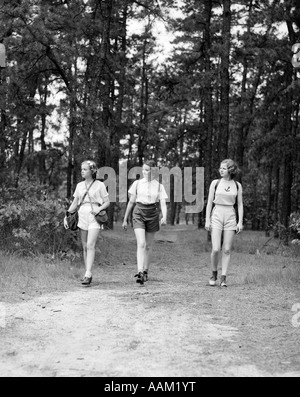 1940s THREE YOUNG WOMEN WALKING IN WOODS HIKING Stock Photo