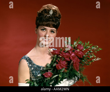 1960s YOUNG WOMAN PROM BEAUTY QUEEN DEBUTANTE HOLDING FLOWERS FLORAL ROSES Stock Photo